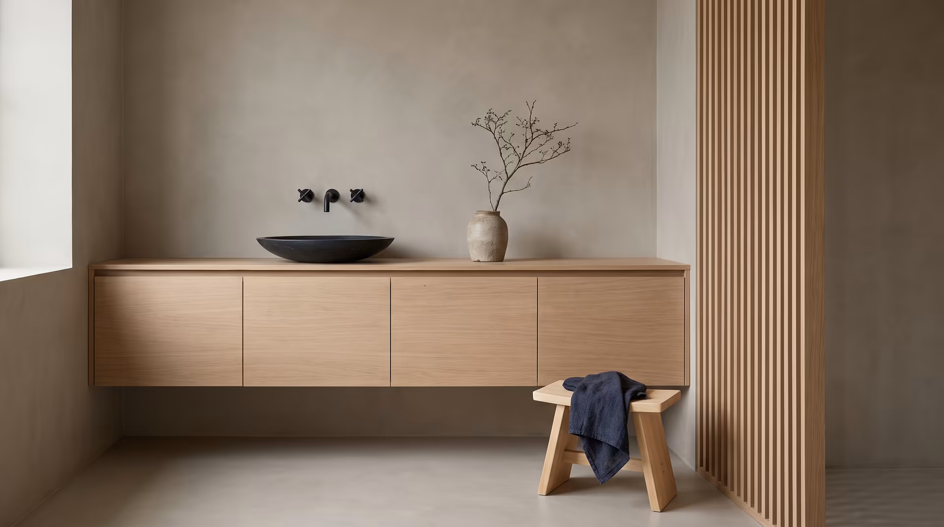 Japandi bathroom with a floating oak vanity, a black stone basin, wall-mounted taps and a slatted wood screen